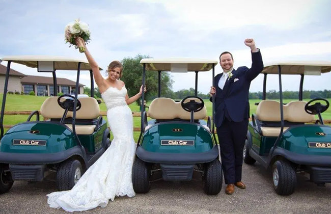 Happy bride and groom celebrating in front of row of golf carts